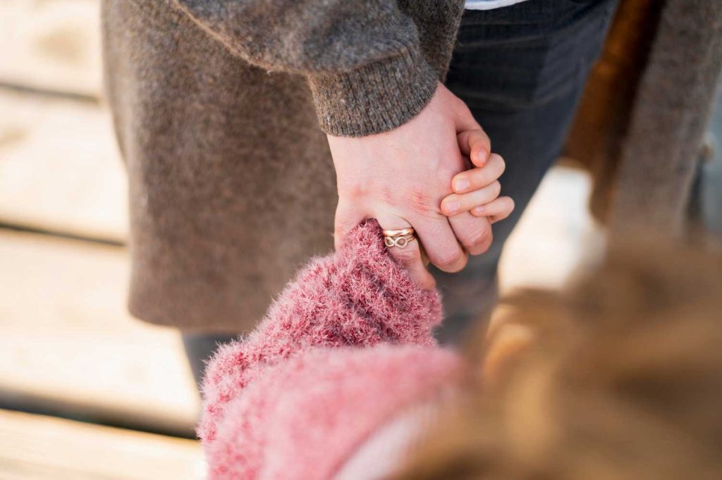 A close-up of a parent holding a child’s hand, symbolizing emotional support and connection in child custody cases handled by Davis & Associates in Columbus.