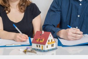 husband and wife with a model of a house on a table between them