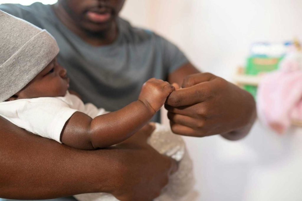 A father gently holding his baby’s hand, symbolizing care and paternal love in the context of father’s rights and paternity cases handled by Davis & Associates in Columbus.