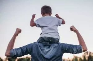 son riding on his father's shoulders